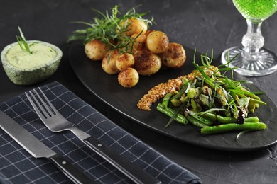 Photo of Delicious salad with tarragon, mustard and grilled potatoes served on black textured table