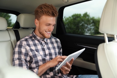 Attractive young man using tablet in luxury car