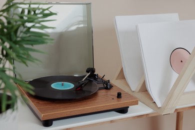 Stylish turntable with vinyl record on white table indoors