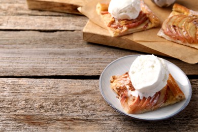 Photo of Pieces of freshly baked apple pie and ice cream on old wooden table. Space for text