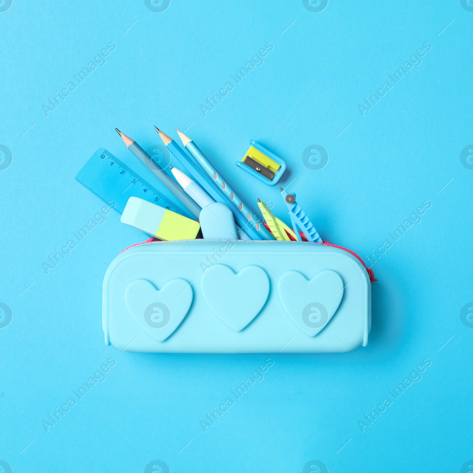 Image of Pencil case and different stationery on light blue background, flat lay. Back to school