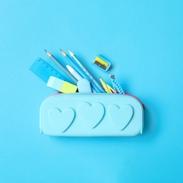 Pencil case and different stationery on light blue background, flat lay. Back to school