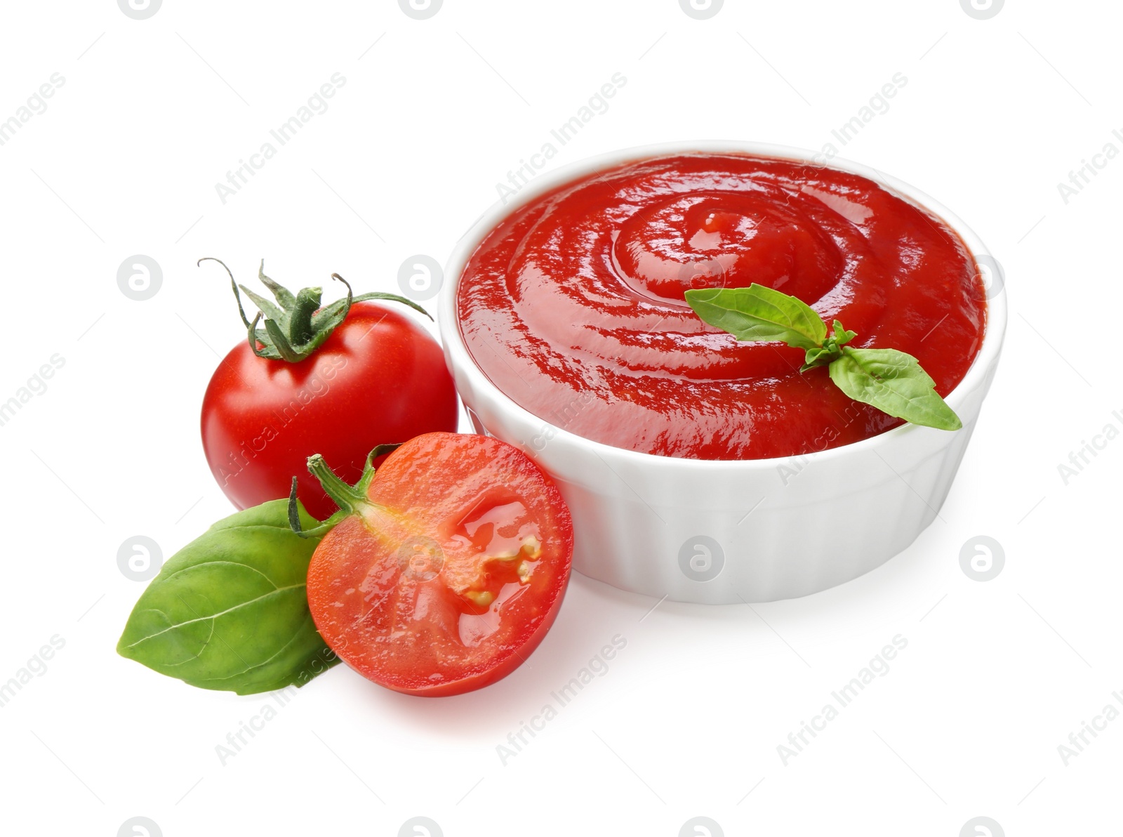 Photo of Tasty ketchup in bowl, basil and fresh tomatoes isolated on white