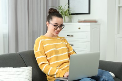 Home workplace. Happy woman working on laptop on sofa in room