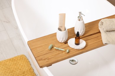 Photo of Different personal care products and accessories on bath tub in bathroom