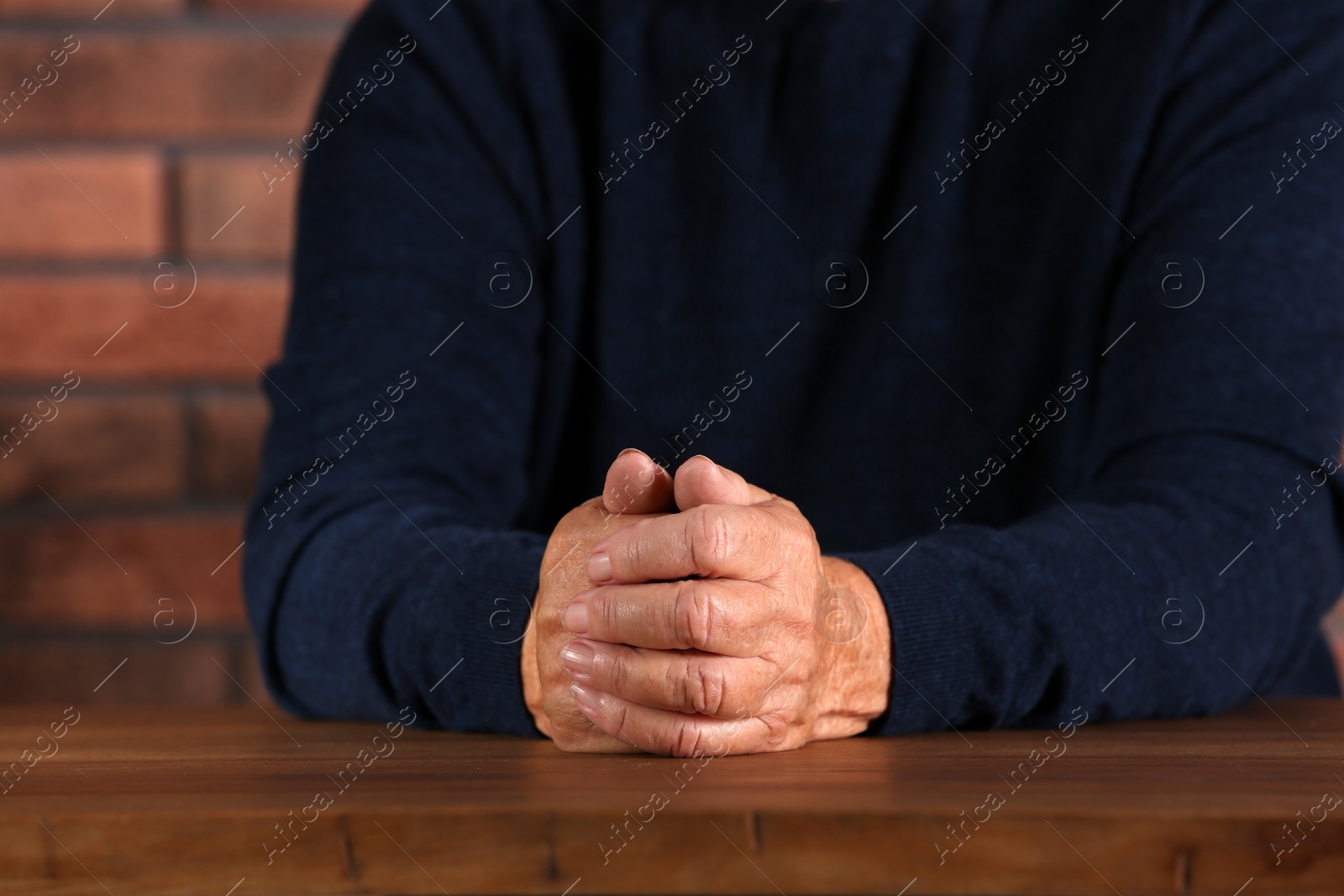 Photo of Poor elderly woman sitting at table, focus on hands