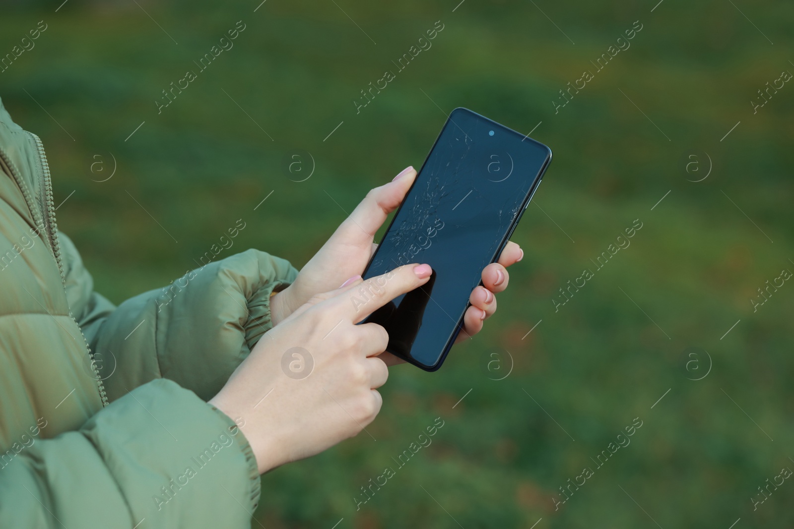 Photo of Woman holding damaged smartphone outdoors, closeup. Device repairing