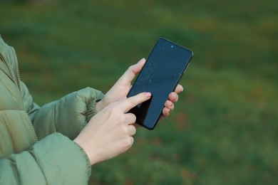 Woman holding damaged smartphone outdoors, closeup. Device repairing