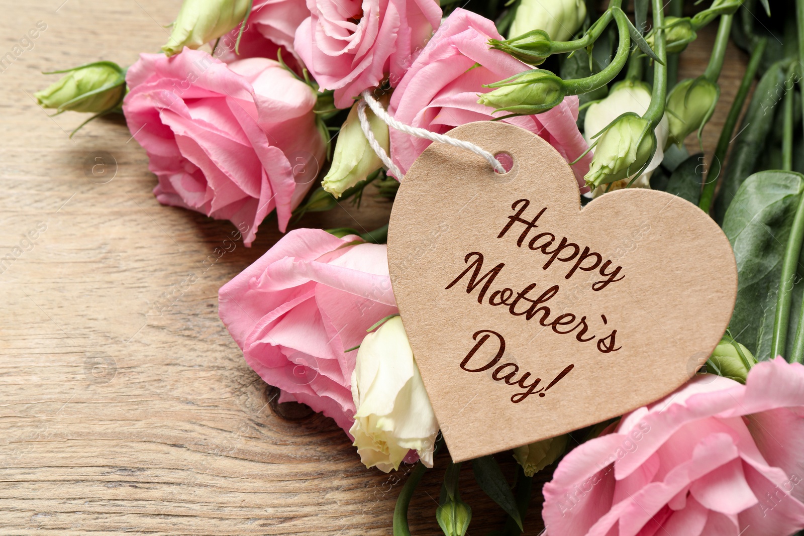 Image of Happy Mother's Day. Heart shaped greeting label and beautiful flowers on wooden table