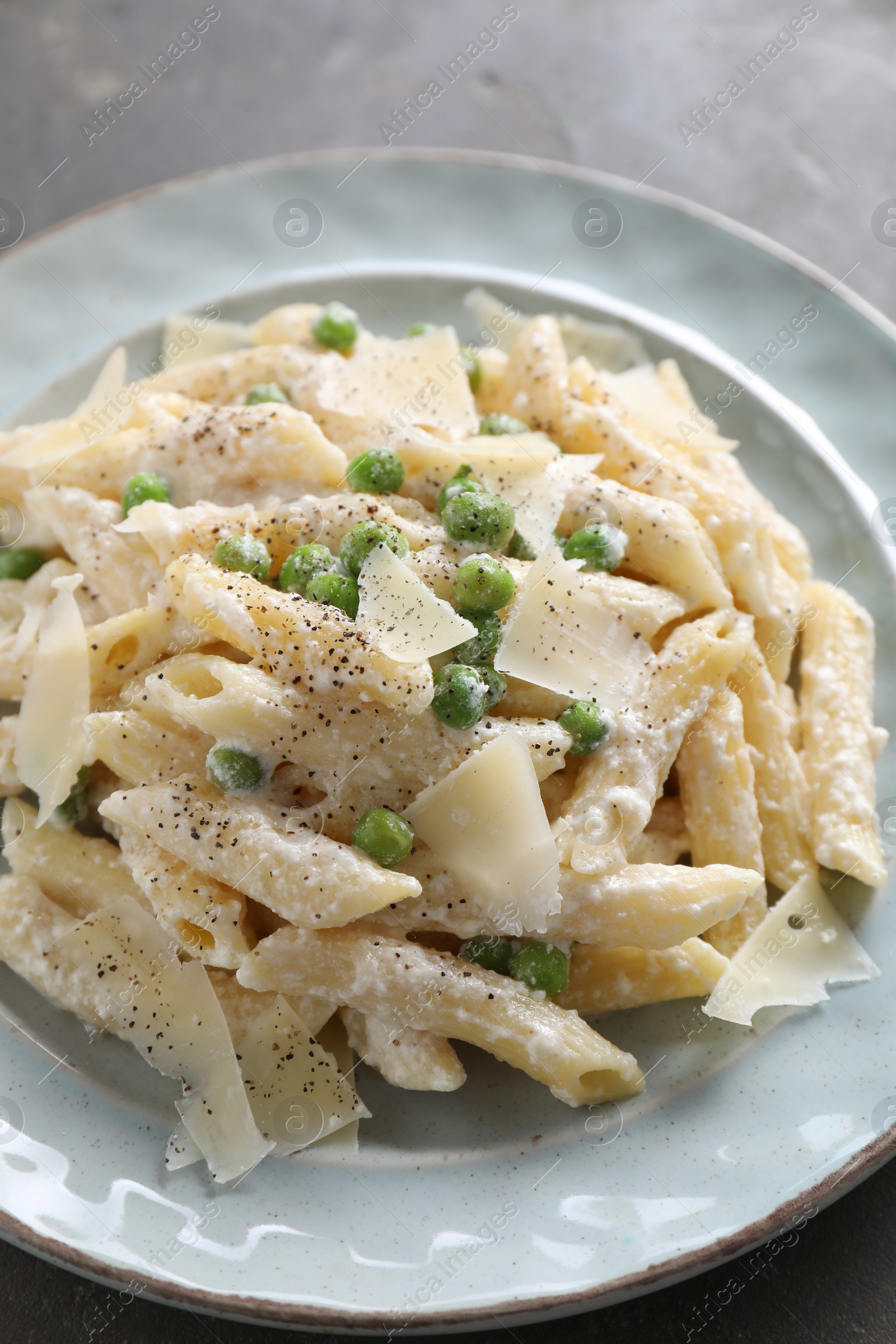 Photo of Delicious pasta with green peas, cheese and creamy sauce on grey table