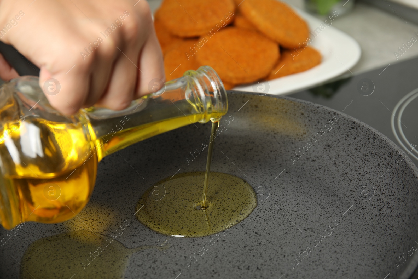 Photo of Woman adding oil on frying pan, closeup. Cooking breaded cutlets