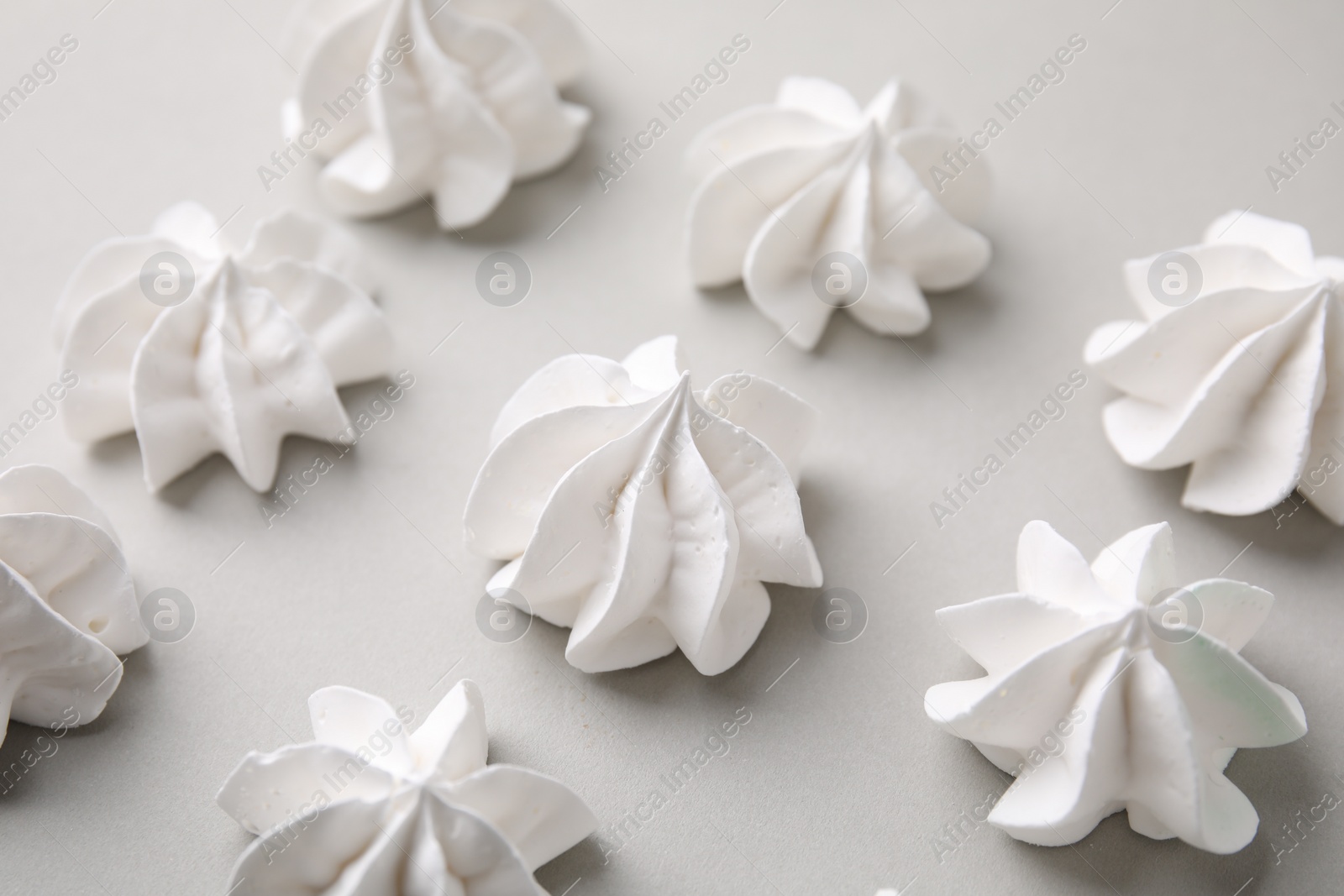 Photo of Tasty meringue cookies on light grey background, closeup