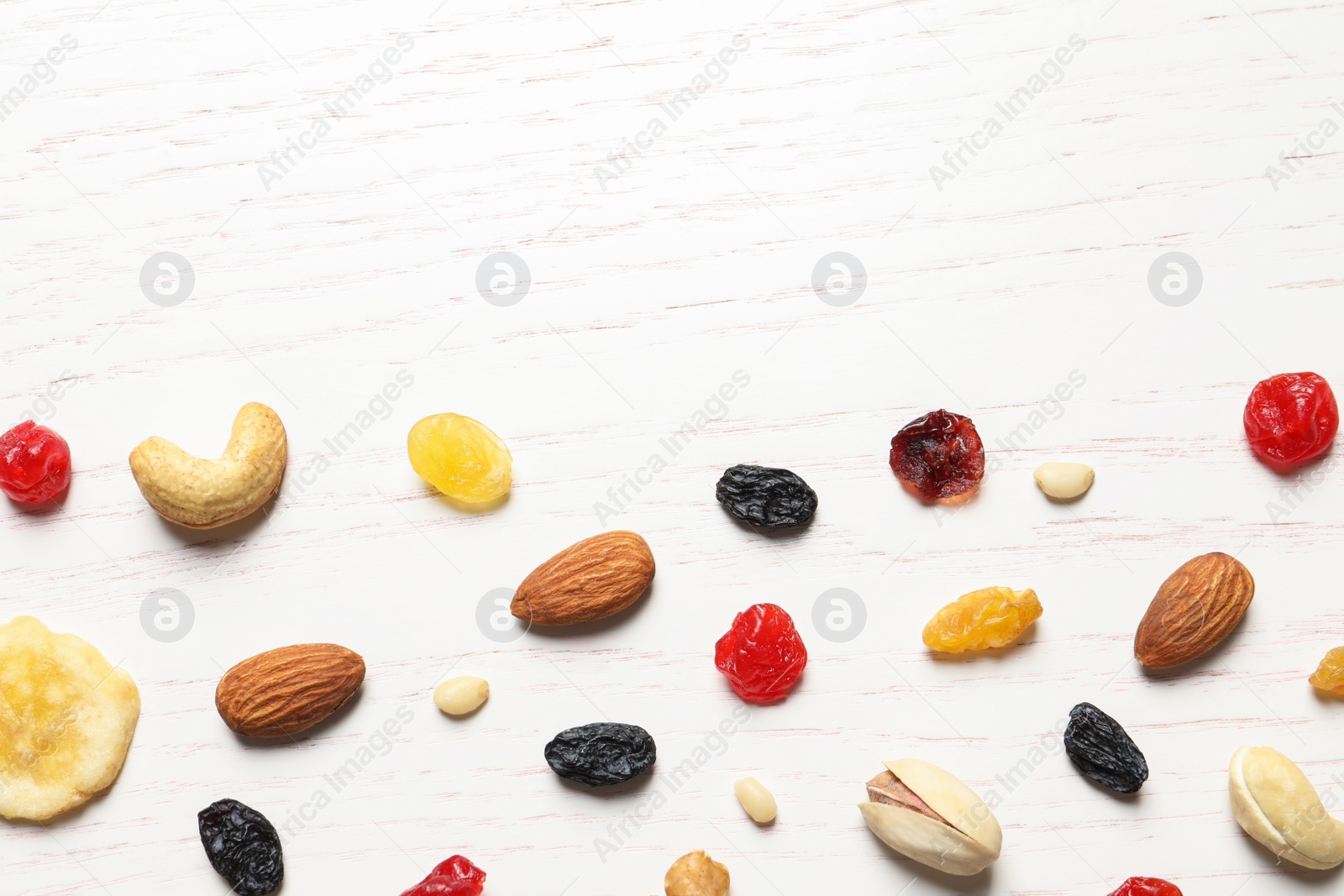 Photo of Flat lay composition of different dried fruits and nuts on wooden background. Space for text