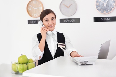 Female receptionist talking on phone at workplace in hotel