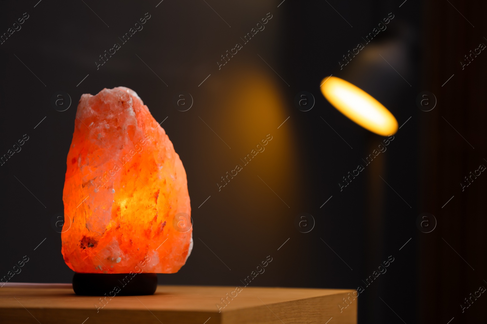 Photo of Himalayan salt lamp on table in room. Space for text