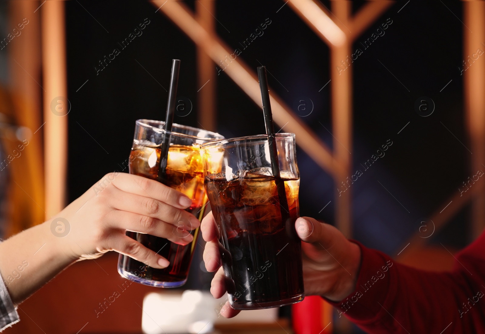 Photo of Young couple with glasses of refreshing cola indoors, closeup