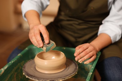 Photo of Clay crafting. Woman making bowl on potter's wheel indoors, closeup