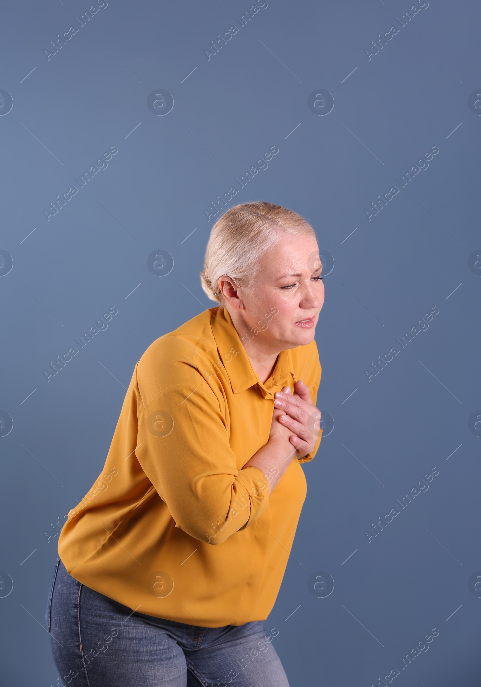 Photo of Mature woman having heart attack on color background