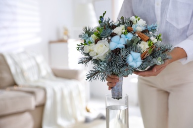 Photo of Woman putting beautiful wedding winter bouquet in vase at home, closeup. Space for text