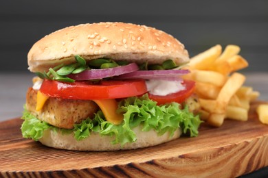 Delicious tofu burger served with french fries on wooden board, closeup