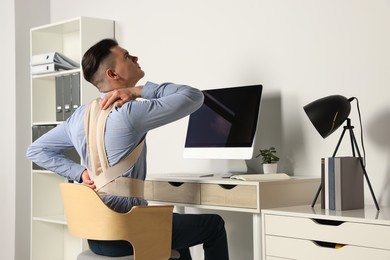 Man with orthopedic corset working on computer in room