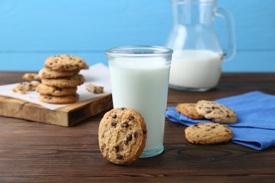 Photo of Delicious chocolate chip cookies and glass of milk on wooden table