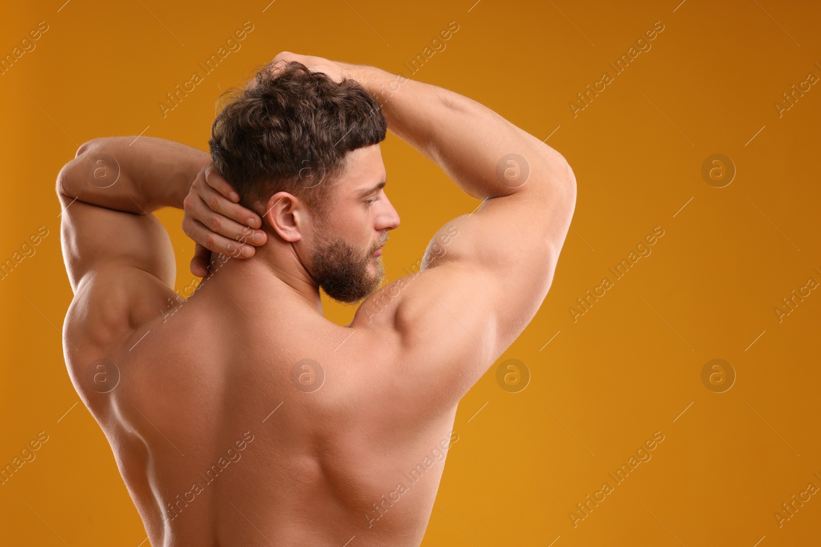 Photo of Muscular man on orange background, back view. Sexy body