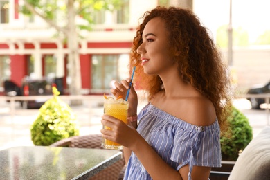 Photo of Happy African-American woman with glass of natural lemonade in cafe. Detox drink