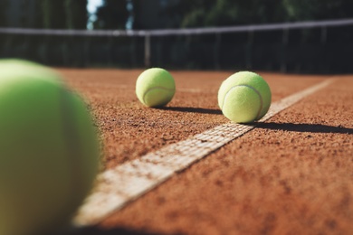 Bright yellow tennis balls on clay court