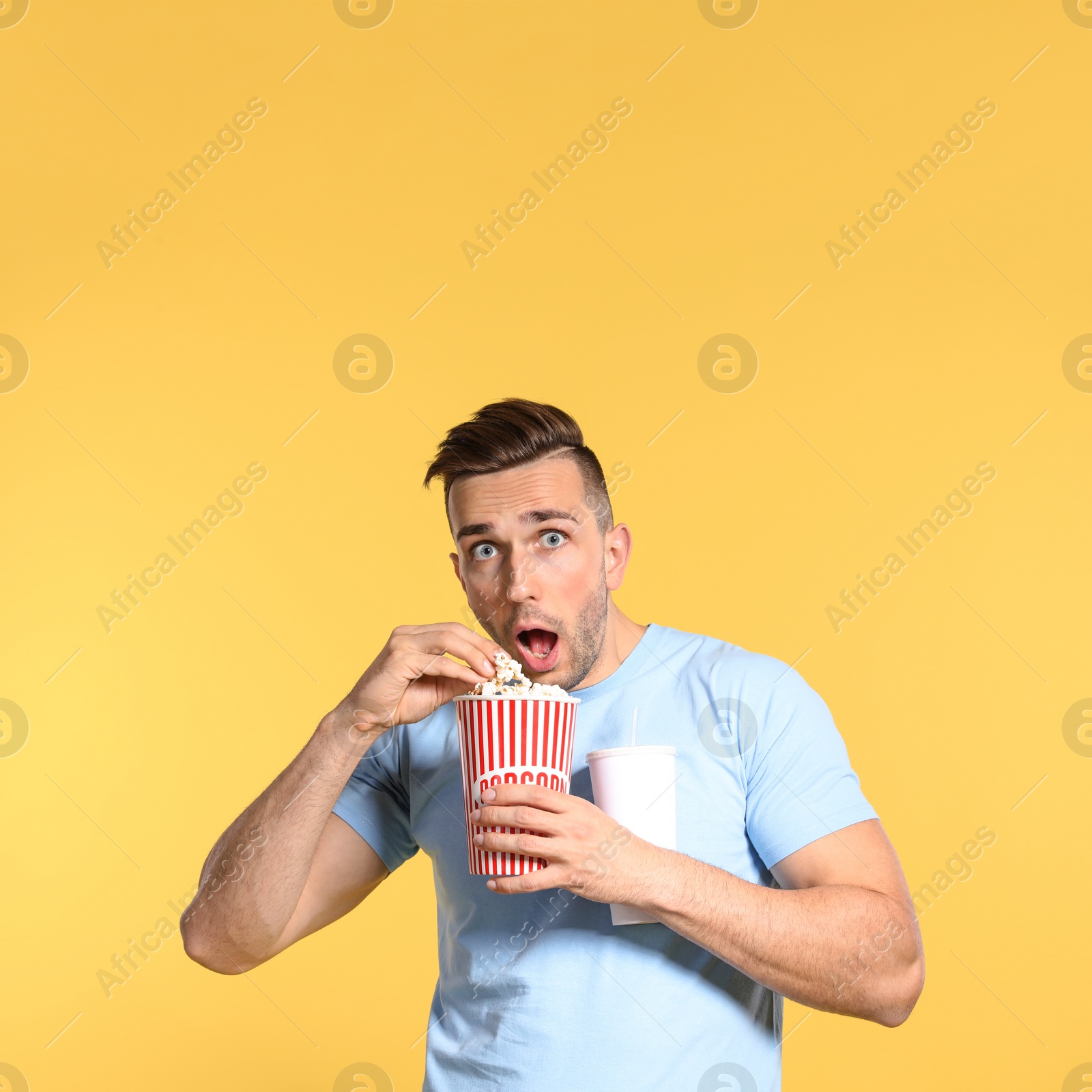 Photo of Emotional man with popcorn and beverage during cinema show on color background