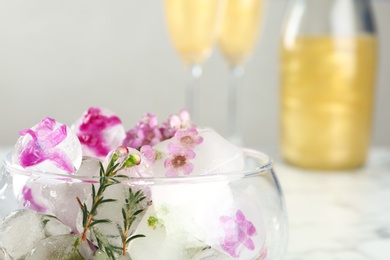 Photo of Glass with floral ice cubes on blurred background, closeup. Space for text