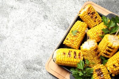 Tasty grilled corn on grey table, top view. Space for text