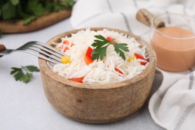 Photo of Bowl of delicious rice with vegetables and parsley served on light gray table, closeup