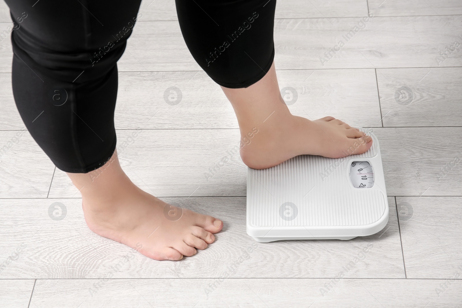 Photo of Overweight woman using scales indoors