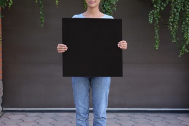 Photo of Woman holding blank poster outdoors. Mockup for design