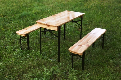 Photo of Wooden picnic table with benches on green grass