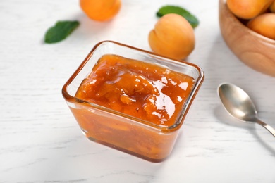 Photo of Bowl with tasty apricot jam on table