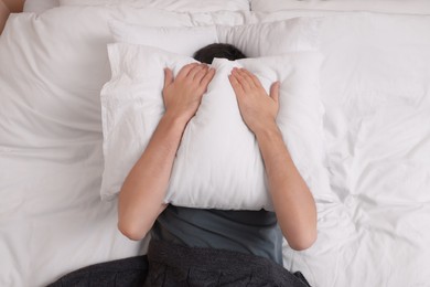 Photo of Man covering his face with pillow in bed, top view