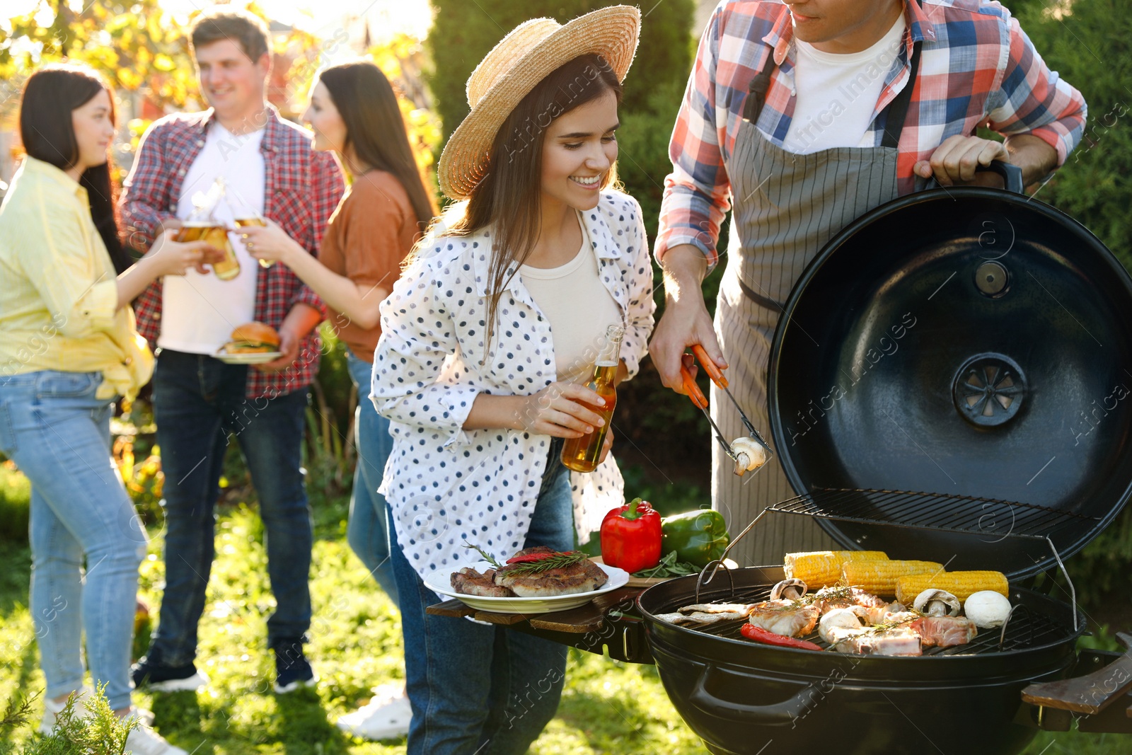 Photo of People with drinks having barbecue party outdoors