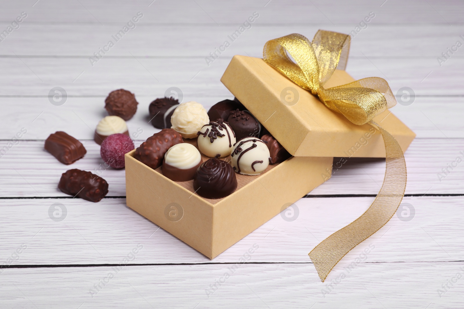 Box with tasty chocolate candies on white wooden table Photo of Box with tasty chocolate candies on white wooden table
