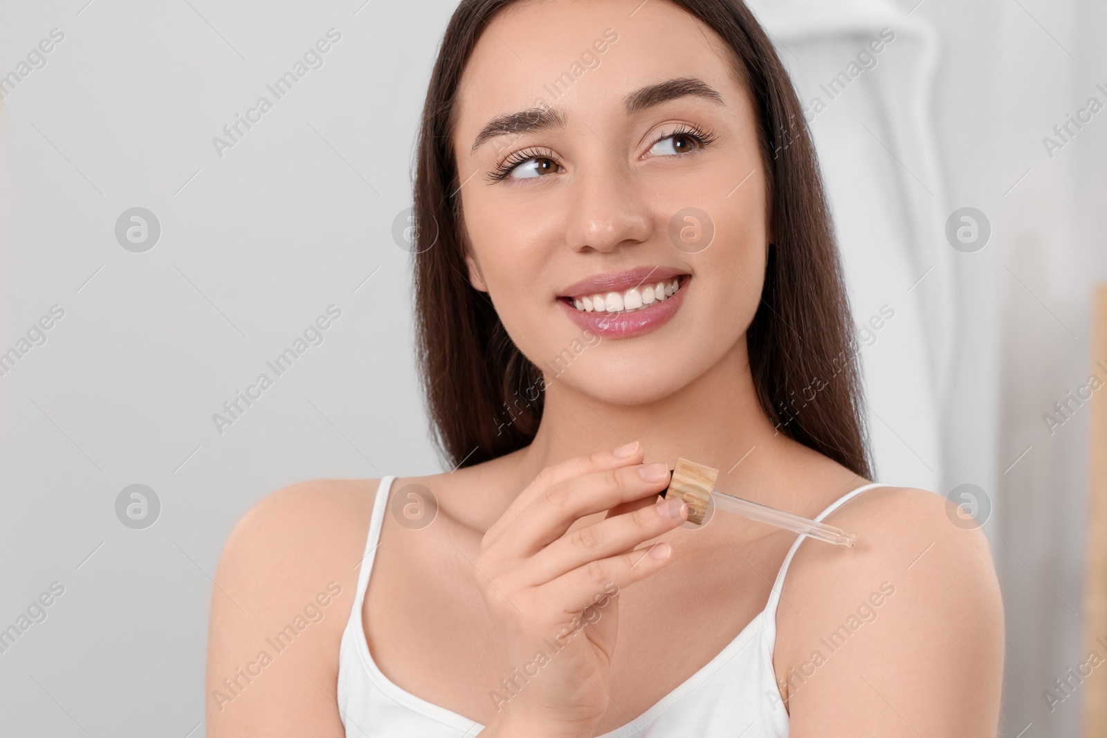 Photo of Woman applying essential oil onto shoulder in bathroom, closeup