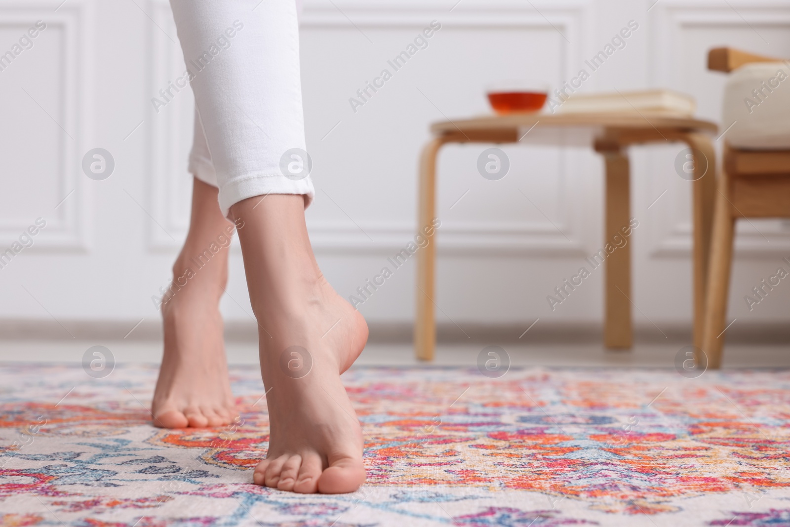 Photo of Woman standing on carpet with pattern at home, closeup. Space for text