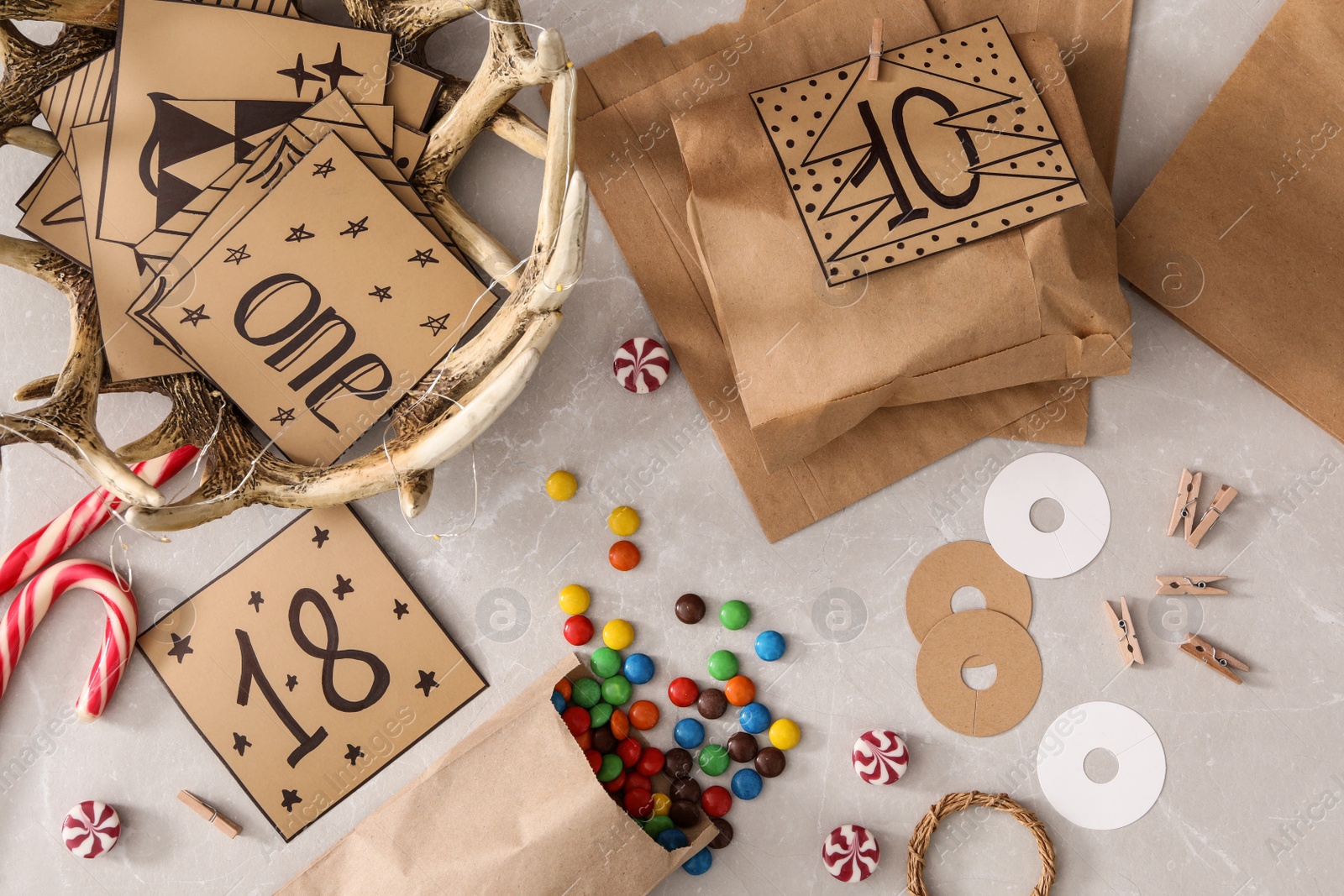 Photo of Flat lay composition with paper bags and treats on grey marble table. Creating advent calendar