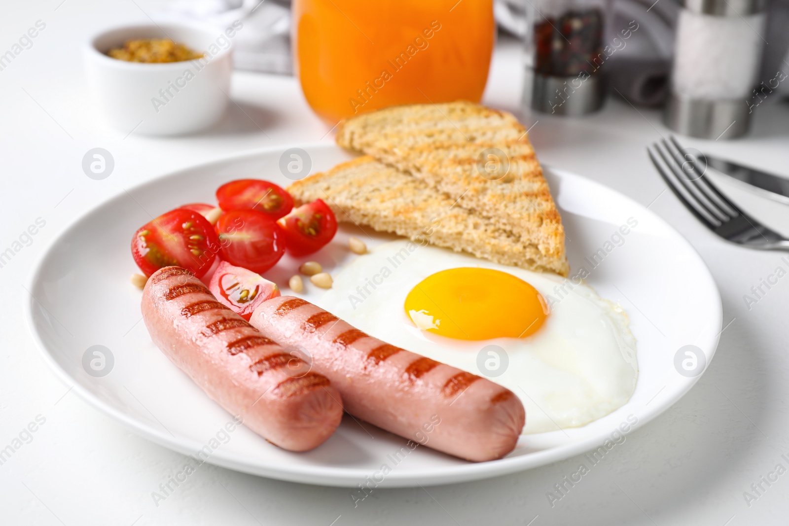 Photo of Tasty breakfast with fried egg and sausages served on white table