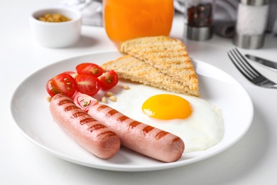 Photo of Tasty breakfast with fried egg and sausages served on white table