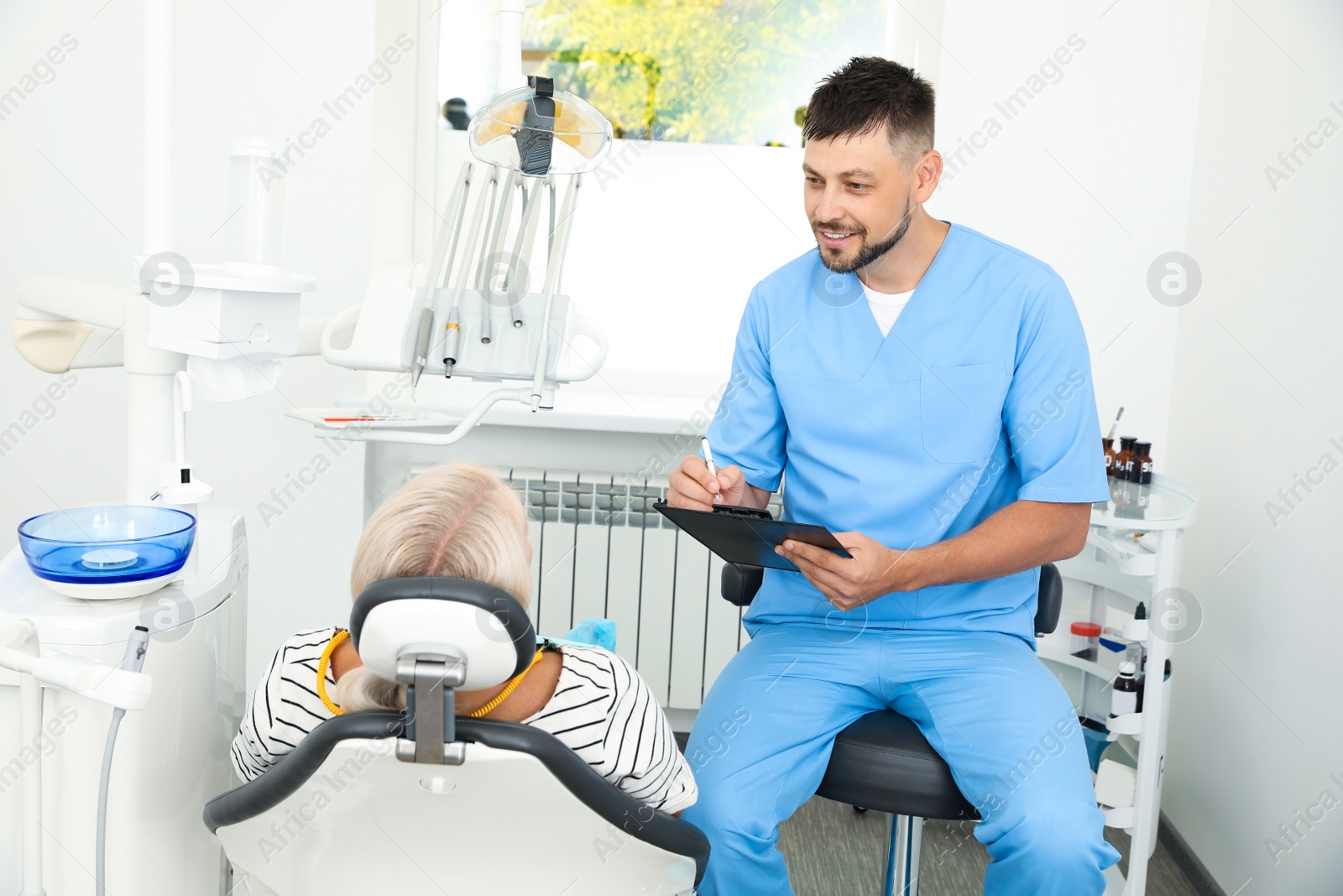 Photo of Professional dentist working with patient in clinic