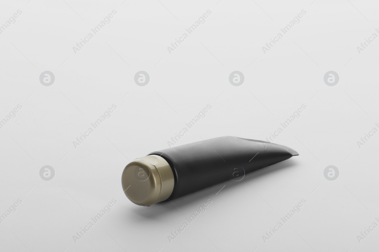 Photo of Black tube against white background. Cosmetic product for men