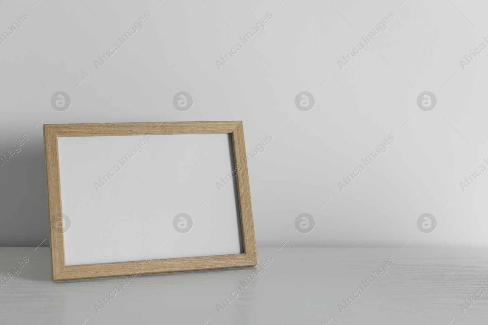 Photo of Empty square frame on white wooden surface, space for text