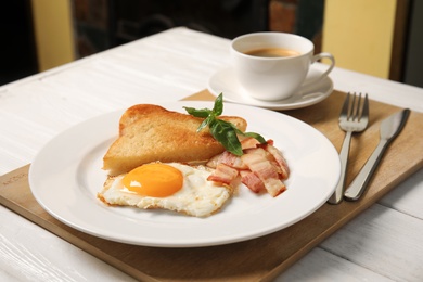 Fried egg with bacon, toasted bread and cup of coffee served for breakfast