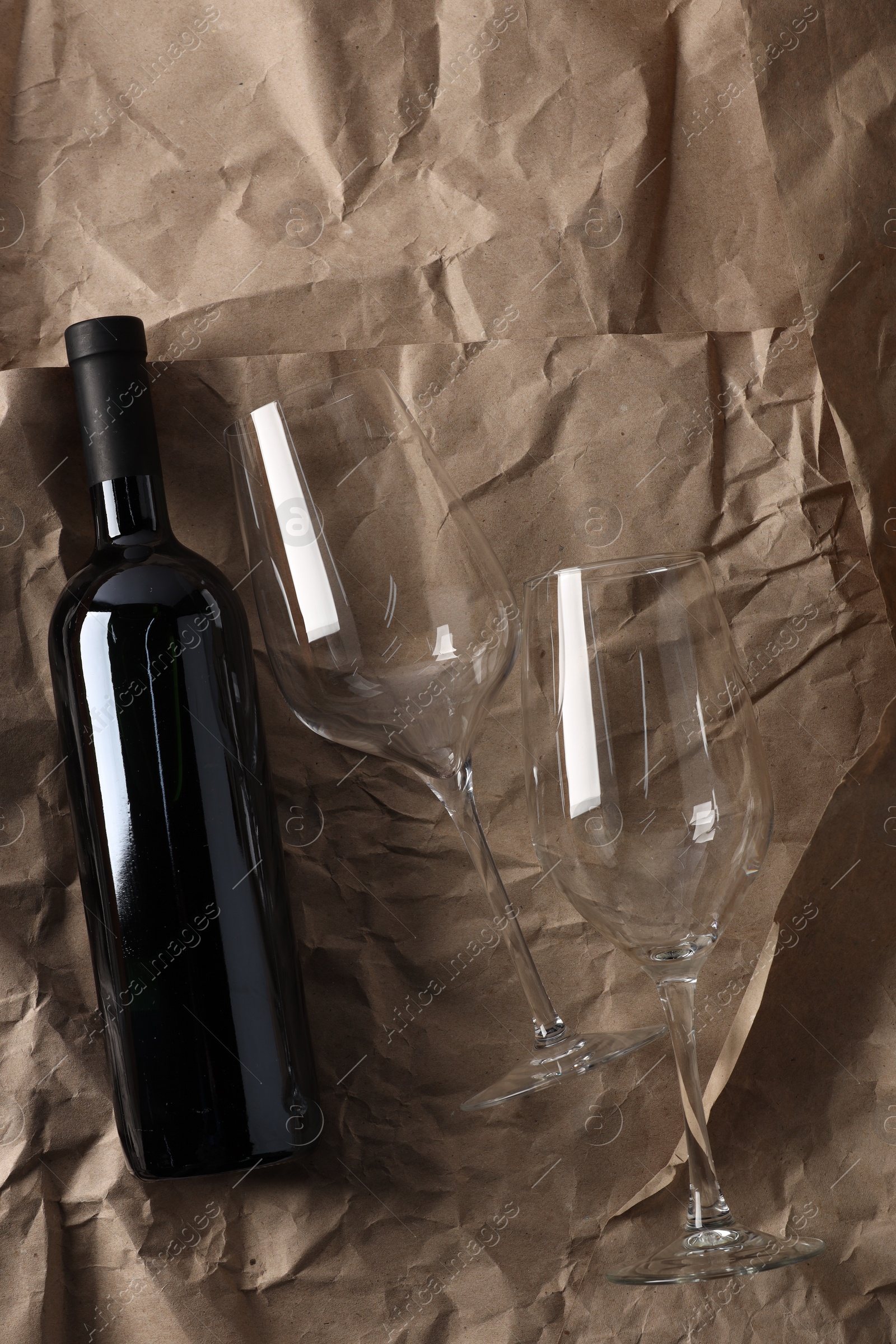 Photo of Stylish presentation of delicious red wine in bottle and glasses on paper background, top view